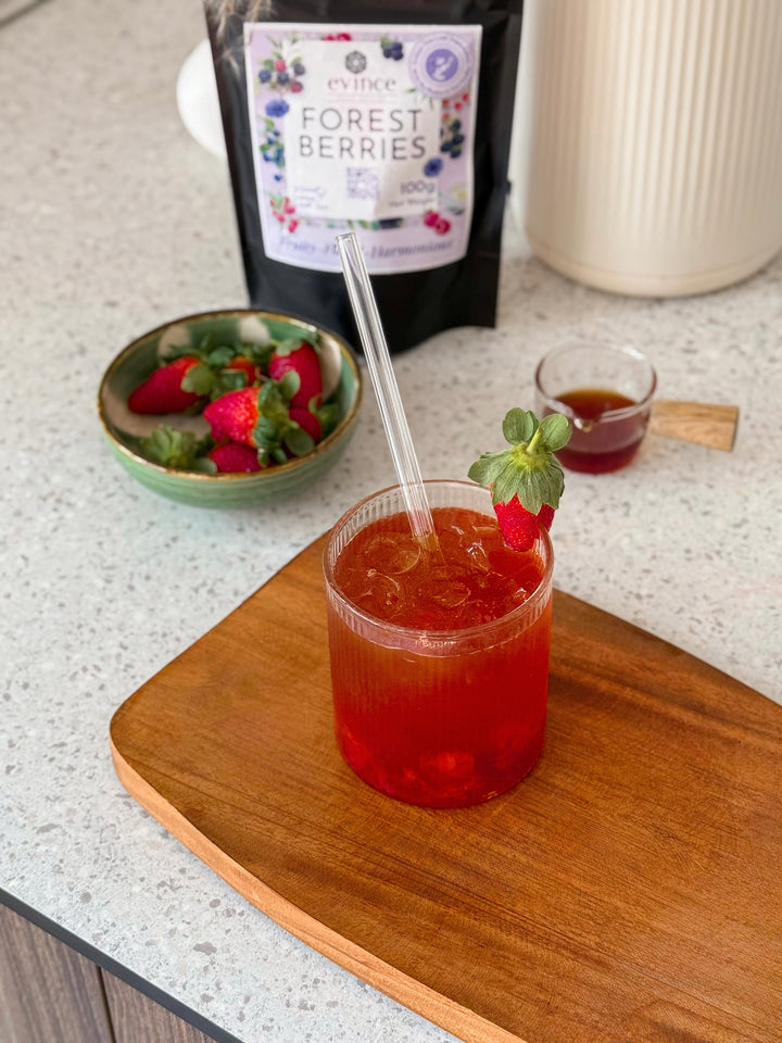 Evince Forest Berries fruity tea prepared in a glass with its pack nearby
