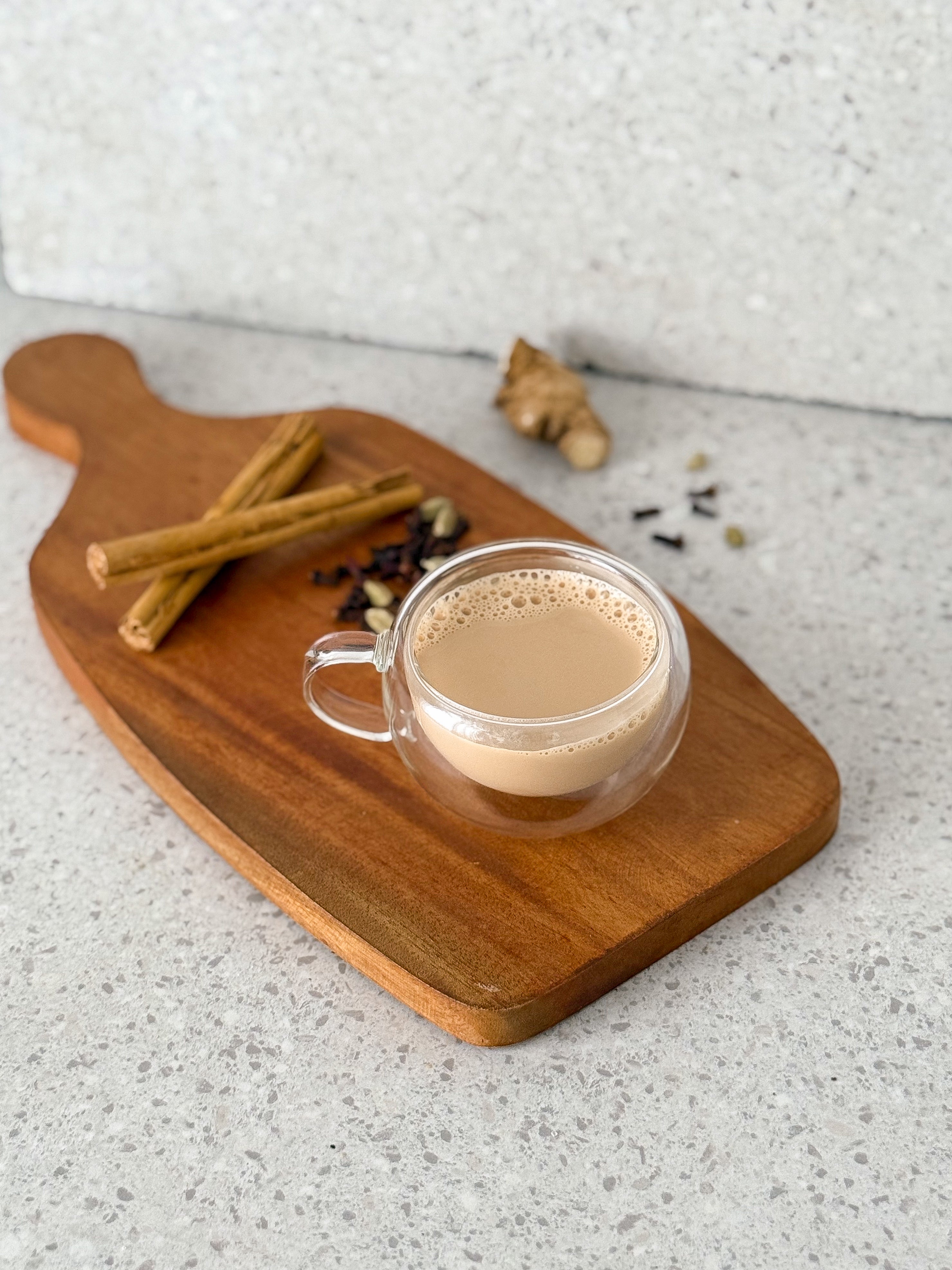 Evince masala chai tea in a glass cup on a wooden board