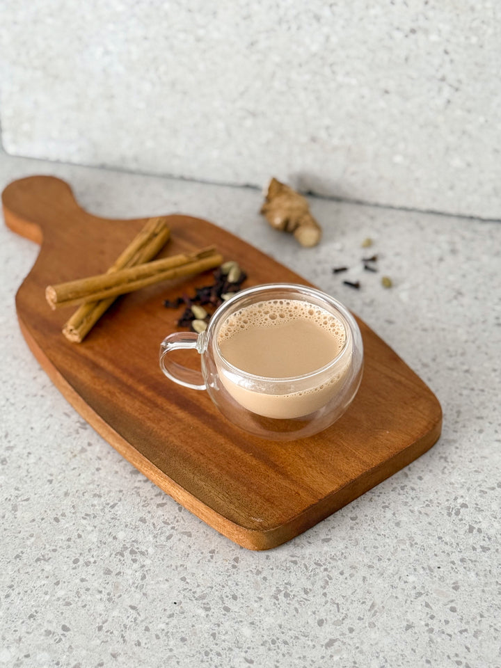 Evince masala chai tea in a glass cup on a wooden board